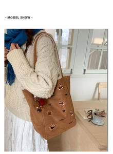 Detail der braunen Shopper-Tasche aus Wildlederimitat mit Hunde-Stickerei und Anhängern
