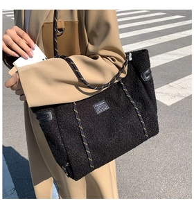 Détail du cabas en polaire noire avec bandoulière tissée et étiquette Fashion Instinct