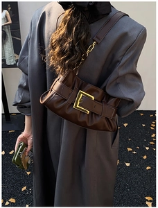 Brown soft leather cloud bag with pleated design and gold buckle in an autumn outdoor scene