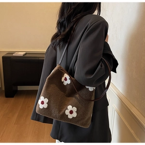 Detail of soft brown plush tote bag featuring white floral patterns and leather straps