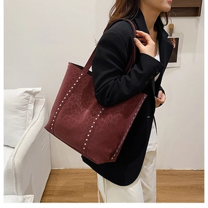 Close-up of burgundy tote bag with leopard pattern and silver rivet details on the side