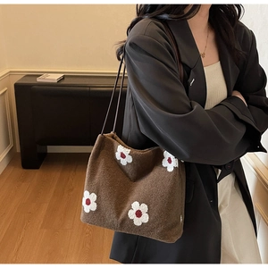 Detail of a brown plush tote bag with 3D floral embroidery and leather shoulder strap