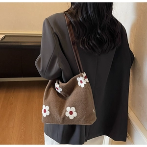Detail view of brown plush tote bag with daisy pattern and leather straps
