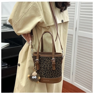 Detail showing leopard print bucket bag with premium brown leather handle and gold logo