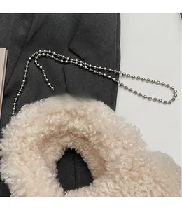 Dettaglio borsa a secchiello in peluche bianco crema con tracolla a catena a sfere argento