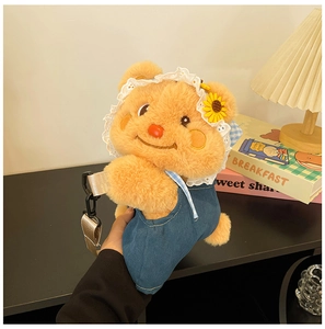 Detail of light brown plush bear bag with denim overalls and lace sunflower hat