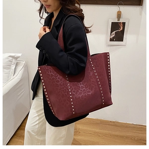 Detail of burgundy leopard print tote bag with metallic stud accents on the side