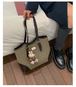 Dettaglio della borsa tote leopardata con finiture in pelle marrone e ciondolo orso