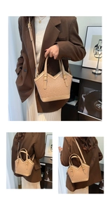 Detail view of khaki woven tote bag with leather straps worn as crossbody and handbag
