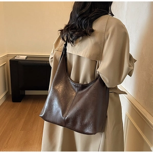 Detail view of large dark brown hobo shoulder bag with textured leather on female model