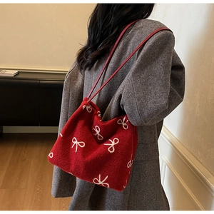 Close-up of red felt tote bag with white bow patterns and leather straps on model
