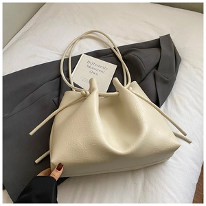 Detail der beigefarbenen Kordelzug-Tasche mit eleganter Kunstleder-Faltenstruktur