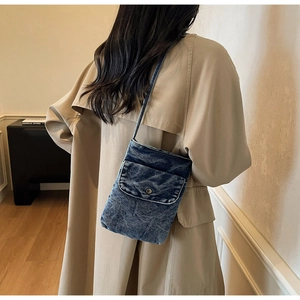Close-up of a minimalist blue denim crossbody phone bag with vintage metal button detail