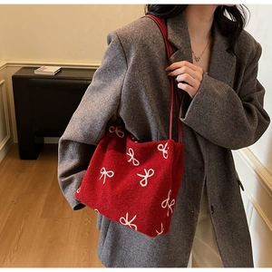 Detailed texture of red wool tote bag featuring white bow embroidery and matching straps