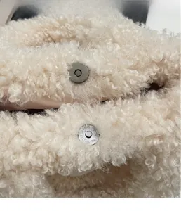 Dettaglio della fibbia magnetica in metallo sulla borsa a secchiello in peluche bianca