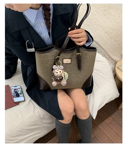 Dettaglio della borsa tote leopardata con manici in pelle marrone e ciondolo a orsetto