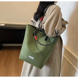 Detail of green checkered canvas tote bag with woven rope handle and brand label