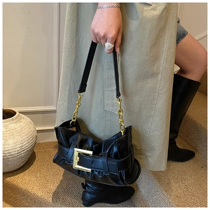 Detail of black pleated shoulder bag with gold chain strap and square buckle buckle