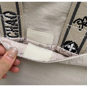 Détail du sac bandoulière en nylon beige montrant le velcro et la sangle jacquard