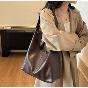 Detail of a large dark brown faux leather tote bag showing textured retro oil wax finish