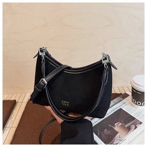 Detail der schwarzen Wildleder-Hobo-Tasche mit Goldlogo und verstellbarem Lederriemen