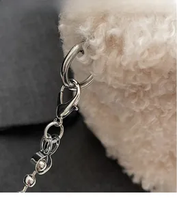 Vista macro dettagliata del moschettone in metallo argento e catena a sfere su borsa peluche