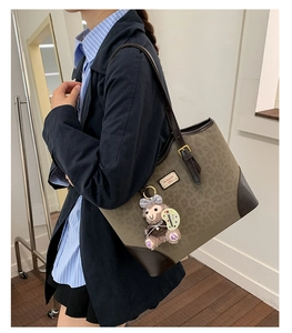 Dettaglio della borsa tote in tela leopardata con finiture in pelle e ciondolo peluche