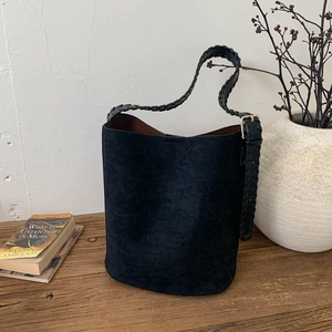 Close-up of the woven leather strap and matte black suede texture of the bucket bag