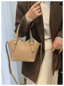 Straw tote bag with brown leather trim and adjustable shoulder strap worn by a model