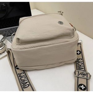 Détail du sac bandoulière beige en nylon avec tissu texturé et sangle à motifs
