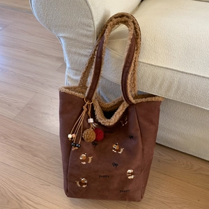 Detail einer braunen Wildleder-Tragetasche mit Welpenstickerei und Plüschanhänger