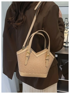 Detail of a woven beige bucket bag styled with a brown blazer for an elegant office look