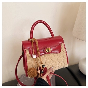 Detail of red leather and beige faux fur handbag with heart texture and golden turn lock