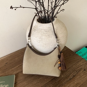 Close-up of suede shoulder bag with brown leather trim and stylish ethnic fringe detail