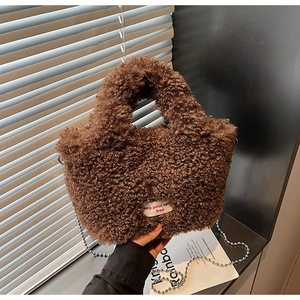 Dettaglio della borsa a secchiello in pile teddy marrone con texture soffice e catena