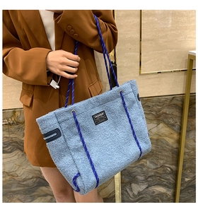 Détail du sac cabas en peau de mouton bleu ciel avec anse tissée rouge et bleue sur modèle