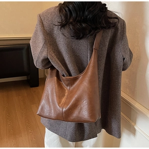 Macro detail of brown leather tote bag showing fine texture and vertical seam design