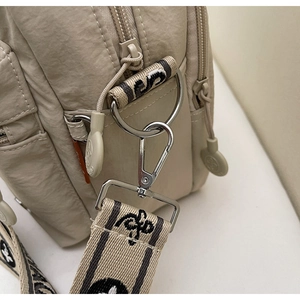 Détails du sac en nylon beige avec fermoirs argentés et bandoulière en jacquard tissé