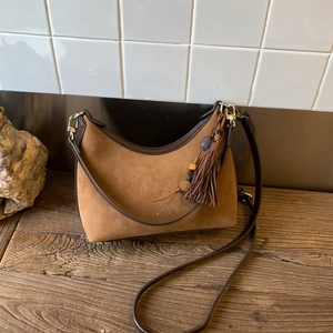 Close-up of retro suede crescent bag featuring leather tassels and wooden beads