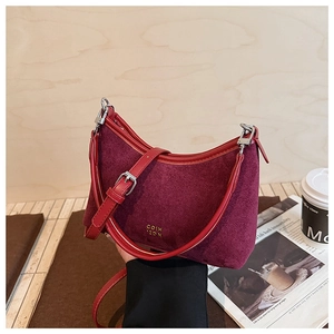 Detail der burgunderroten Wildledertasche mit goldenem Logo und feiner Lederstruktur