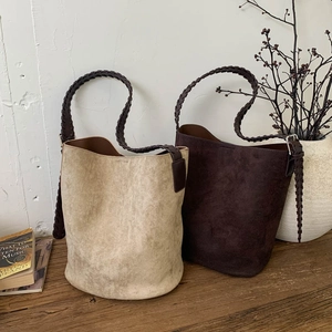 Detailed shot of vintage faux suede bucket bags with thick woven shoulder straps on wood