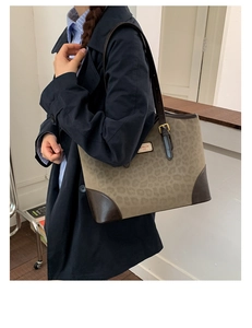 Dettaglio della borsa tote leopardata con manici in pelle marrone e logo