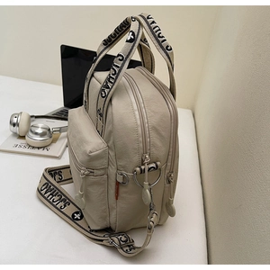 Détail montrant la texture en nylon beige et la bandoulière en jacquard fleuri du sac