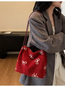 Red canvas tote bag with white bow embroidery and red straps on a fashion model