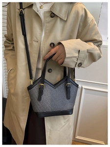 Detail of retro houndstooth tote bag with black leather straps and gold buckle accents