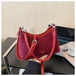 Detailansicht der burgunderroten Wildledertasche mit goldenem Logo und Lederriemen