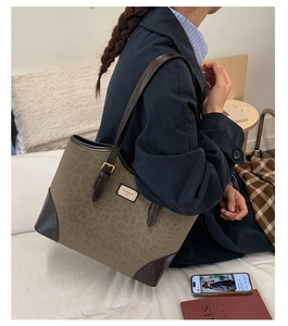 Dettaglio della borsa tote leopardata vintage con finiture in pelle marrone e logo in metallo