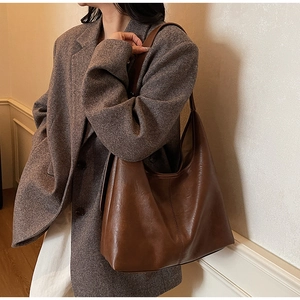 Detailed close-up of a large dark brown leather hobo bag with retro texture and minimalist design