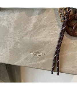 Detail einer grauen Vintage-Tragetasche mit gewebtem Kordelzug und strukturierter Oberfläche