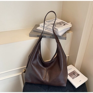 Detail of a large dark brown hobo bag on a minimalist display with elegant leather texture